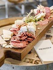 A table of ham and different types of meats and cheese accompanied with green grapes