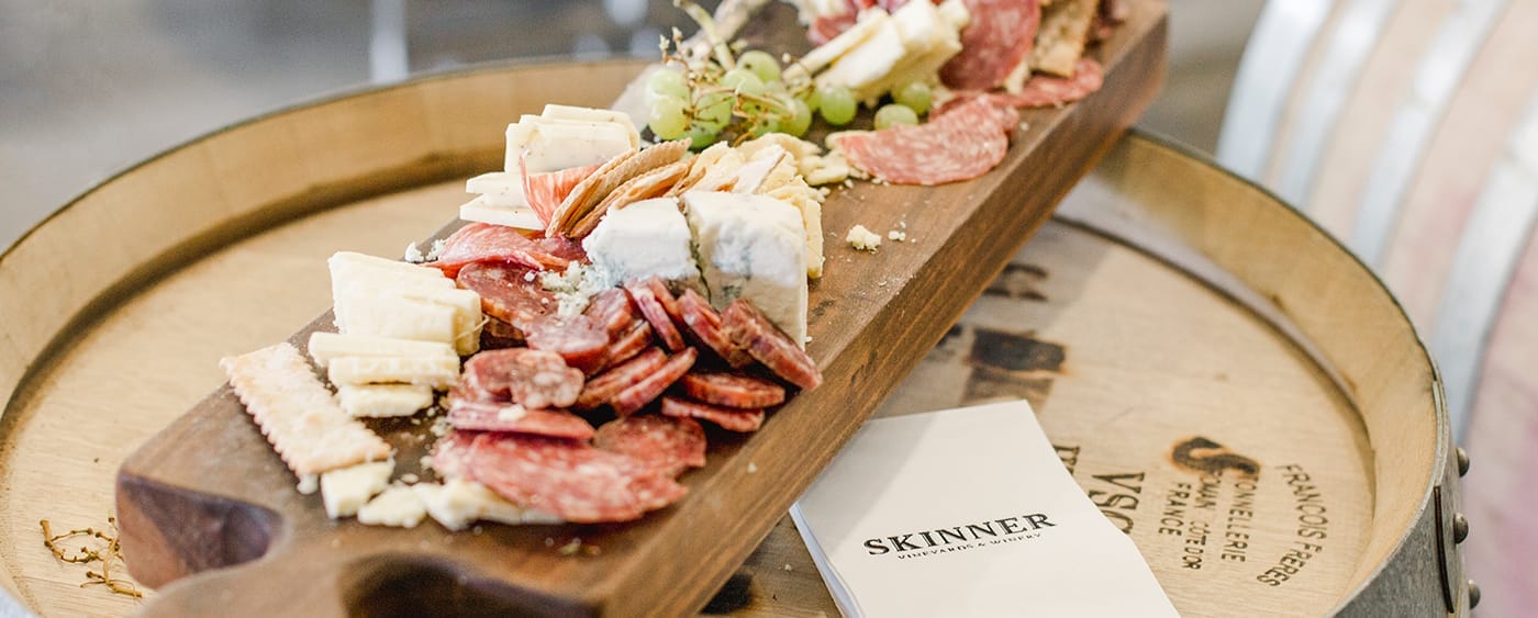 Table with different kinds of meat and cheese and green grapes