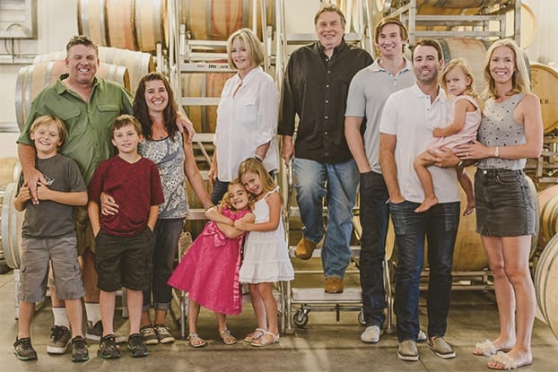 The Skinner family portrait standing in front of the wine barrels